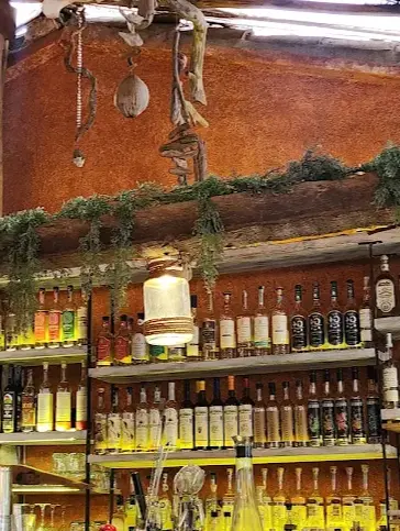 Shelves of tequila bottles behind a rustic bar in Sayulita, highlighted by warm lighting and greenery along wooden beams and clay-toned walls.