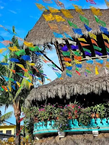 Colorful papel picado flutter above Xochi’s terrace as mezcal and fusion plates flow beneath sunset skies on Mexico’s Pacific Riviera.