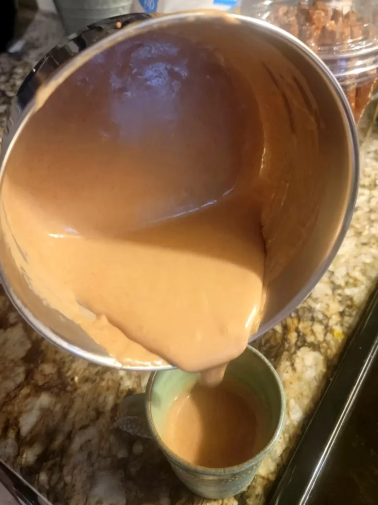 A thick, creamy atole pours into a mug from a pot, evoking slow mornings and traditional kitchen rituals from Mexico.