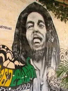 Bold Bob Marley mural with swirling patterns and reggae colors painted on a textured wall, capturing laid-back creative energy in Riviera Nayarit.