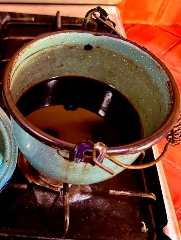 A rustic pot simmers café de olla on the stove, bringing cinnamon-sweet aroma and slow brewing in a traditional kitchen.