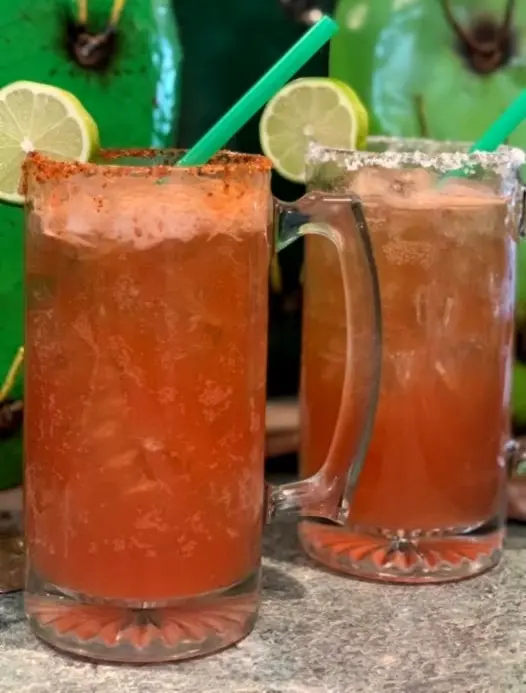 Two chilled cheladas with salted and spiced rims beside lime slices, perfect for laid-back afternoons in Coastal Nayarit.