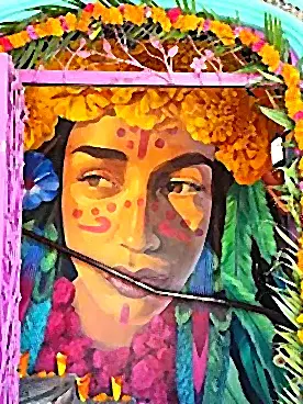 A colorful Día de los Muertos mural framed in pink is decorated with marigolds, greenery, and floral details in a street display.
