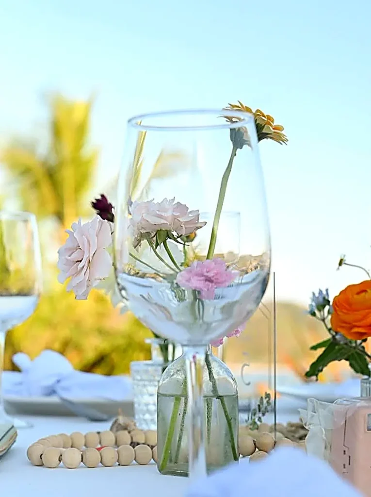 Delicate flowers rest inside glassware on a styled wedding table, catching natural light during an intimate beach celebration near Puerto Vallarta.