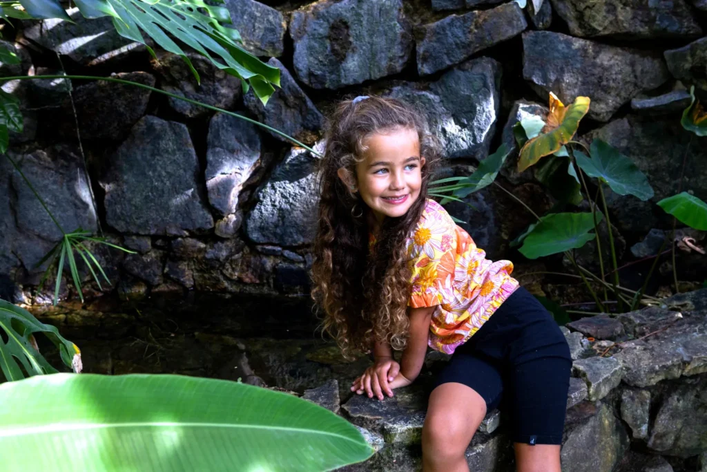 A smiling child relaxes in the lush garden at Amari Boutique Hotel Sayulita, highlighting the peaceful, family-friendly atmosphere.