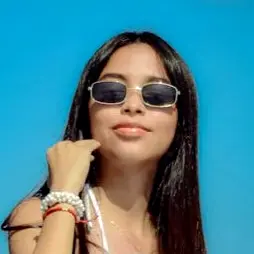 Woman wearing slim sunglasses and bracelets against a bright blue background, vacation-ready style for bright, sunny days.