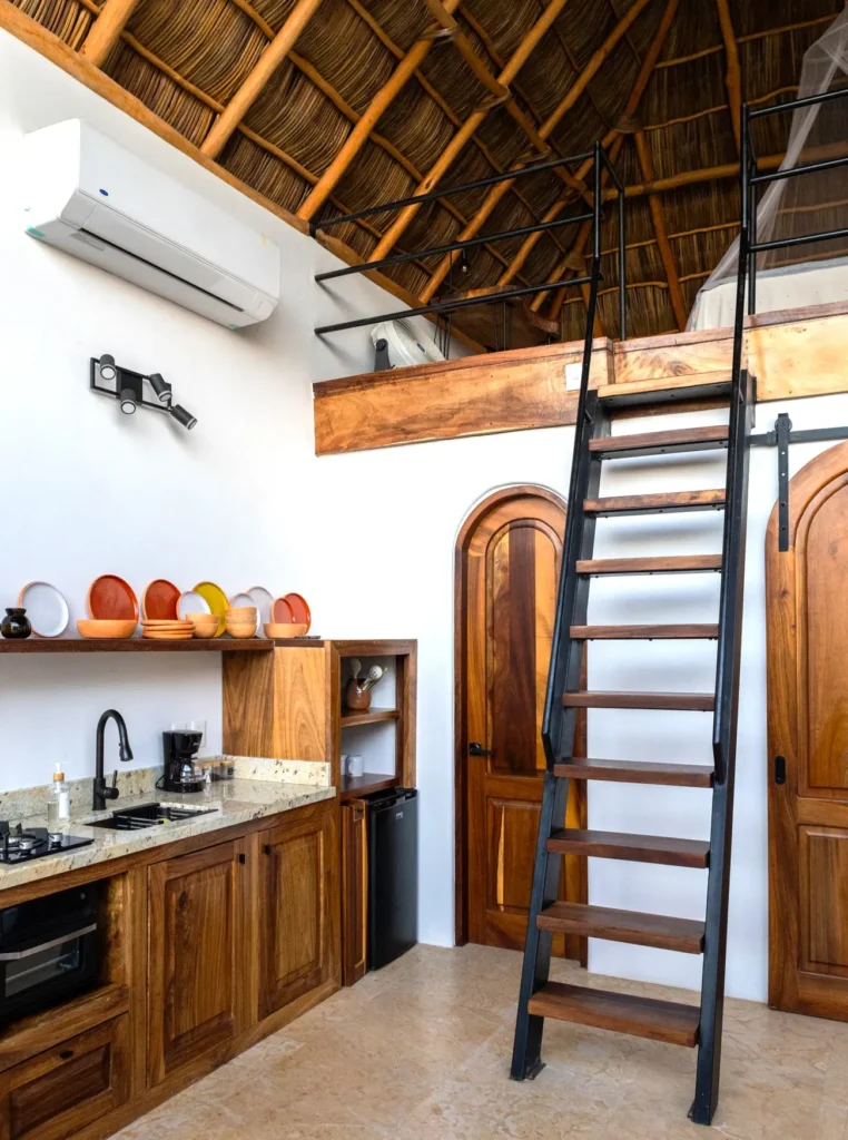 Spacious loft-style suite at Amari Boutique Hotel with a kitchen, warm wood finishes, and stairs to a cozy sleeping loft in Sayulita.