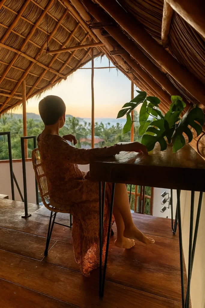 A guest sits beside panoramic ocean views as breezes move through the palapa—quiet morning moments at Amari’s tranquil hillside retreat.