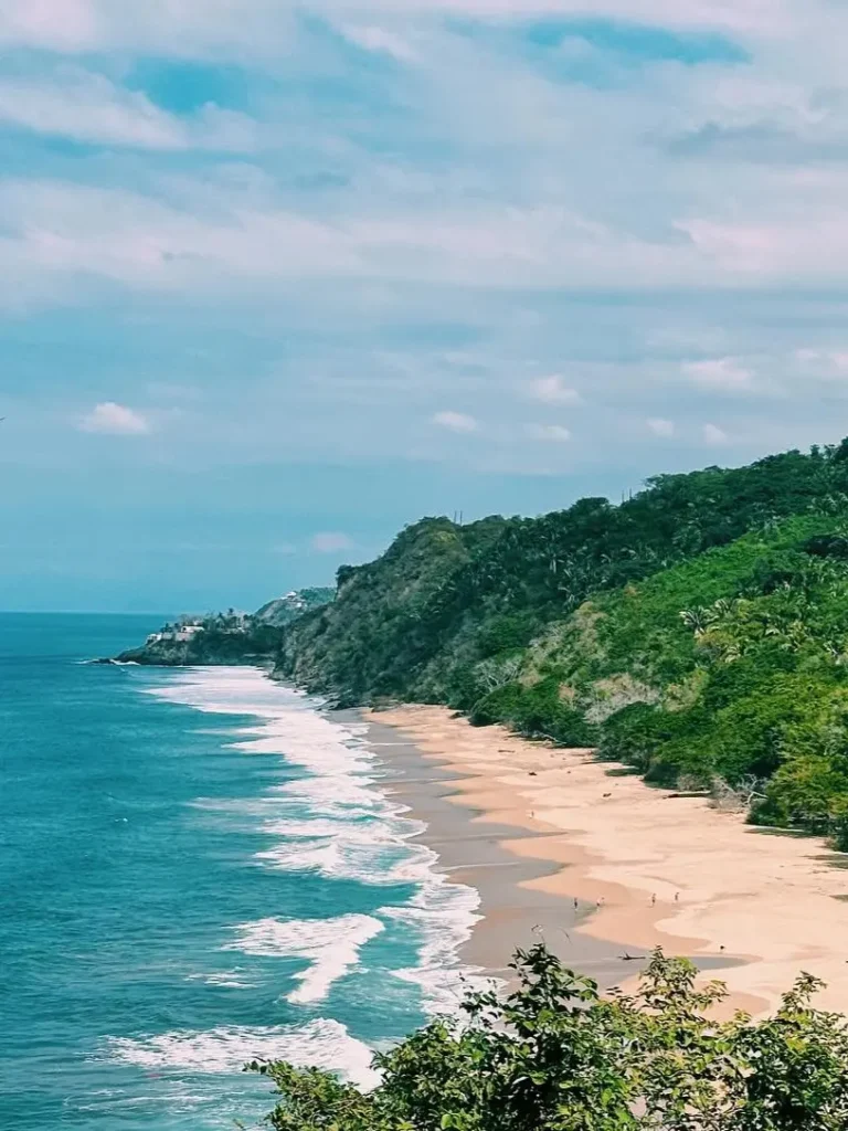 Sweeping view of Playa Malpaso with turquoise surf, soft sand, and jungle cliffs—an open-air escape at sunset along the coastline.
