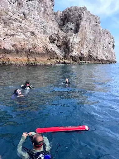 Snorkelers floating in calm water near towering rocky cliffs during a guided swim stop at Parque Nacional Islas Marietas.