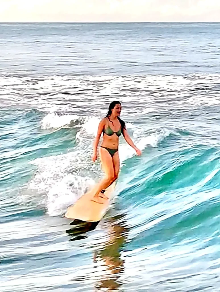 A surfer glides smoothly across a small wave at sunset, capturing effortless balance and the relaxed rhythm of Sayulita, Nayarit.