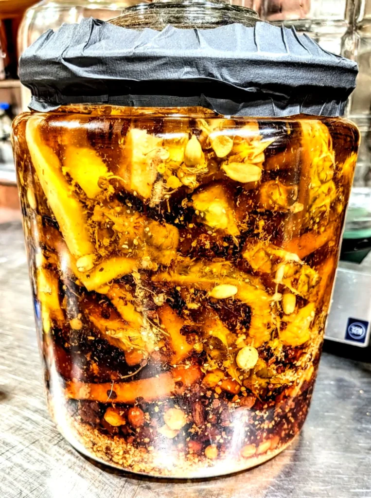 A jar of fermented pineapple tepache with spices and natural bubbles, highlighting tangy sweetness and lively street-market fizz.