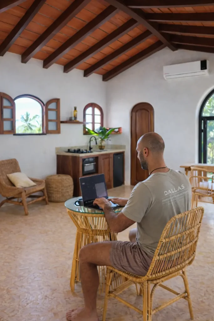 Guest working on a laptop inside a handcrafted studio suite with natural light and wood-beamed ceilings in Riviera Nayarit, supported by strong WiFi.