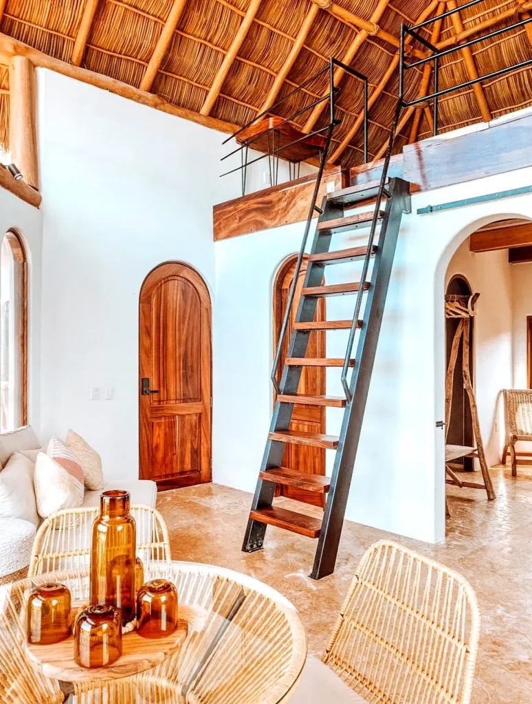 Una luminosa suite tipo loft en Amari Boutique Hotel con un alto techo de palapa, madera artesanal, materiales naturales y amplias áreas de estar.