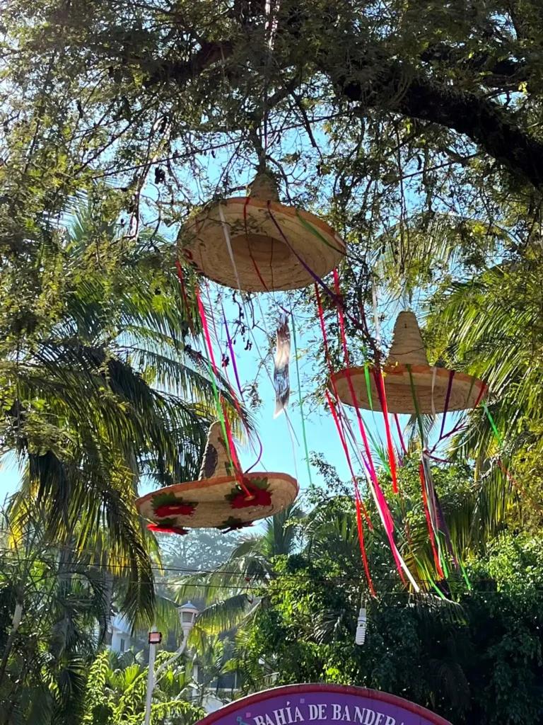 Traditional Mexican sombrero decorations hanging above a lively street during a local celebration.