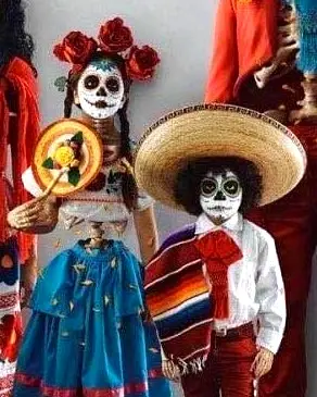 Dos niños con vestimenta tradicional del Día de los Muertos y maquillaje de calavera participan en una colorida celebración cultural mexicana.