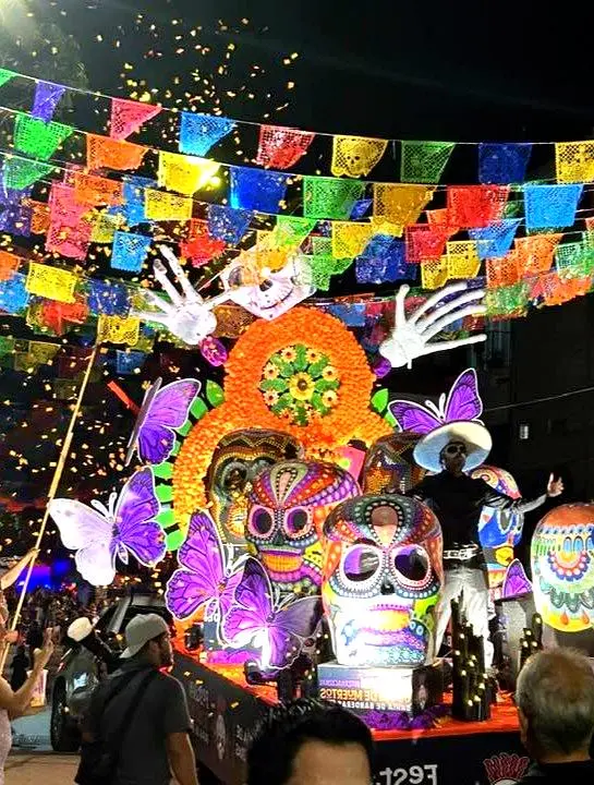 Una colorida carroza del Día de los Muertos con calaveras, cempasúchiles, mariposas y papel picado durante una celebración en Sayulita.