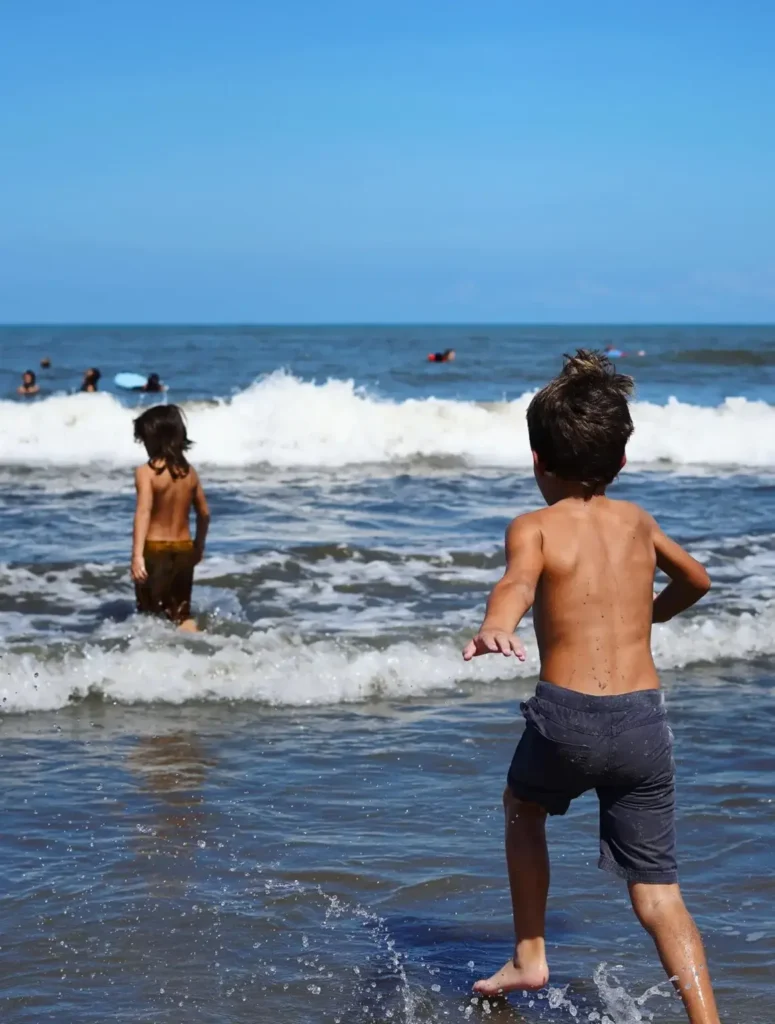 Children playing in the surf on a sandy beach near Sayulita, enjoying warm Pacific waters and a family-friendly Riviera Nayarit setting.