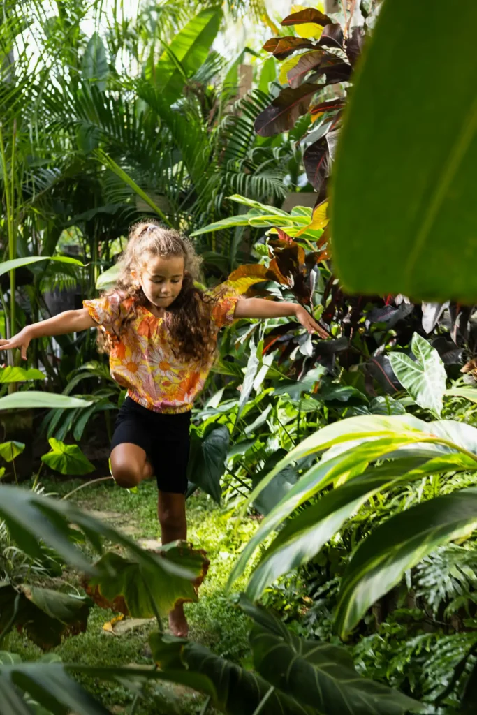 A child explores the lush tropical gardens at Amari Boutique Hotel in Sayulita, surrounded by palms, exotic plants, and peaceful natural spaces.