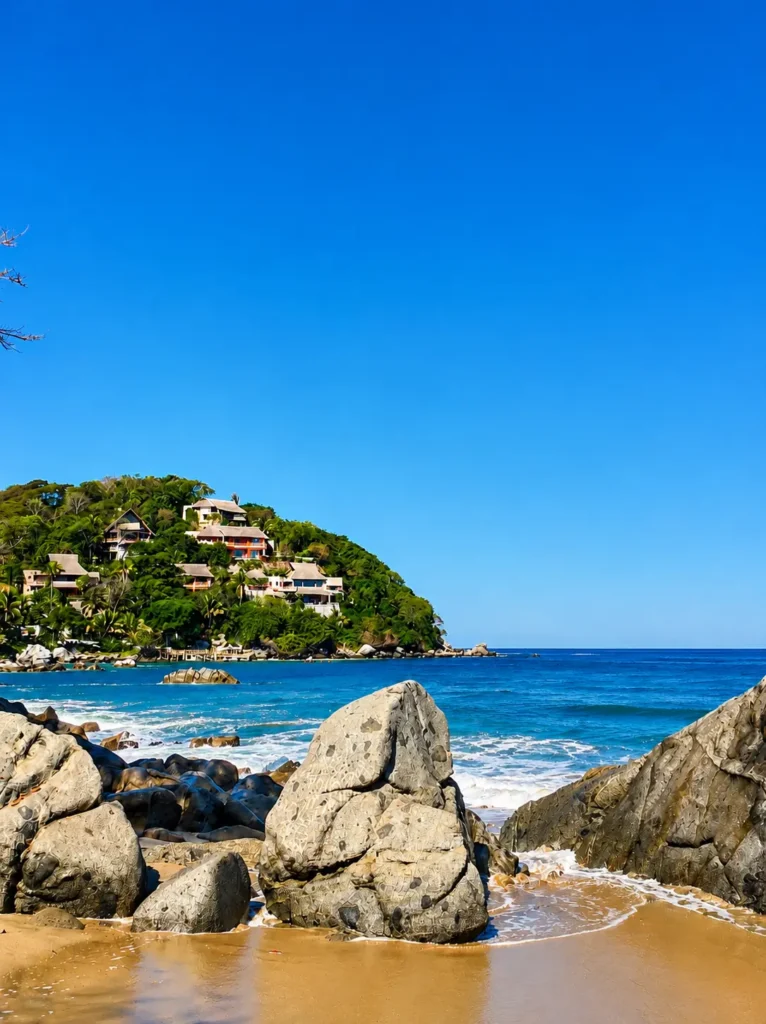 Rocky shoreline and turquoise Pacific waters below Sayulita's lush hillside homes, showcasing the natural beauty and distinctive coastal landscape of this Riviera Nayarit beach town.