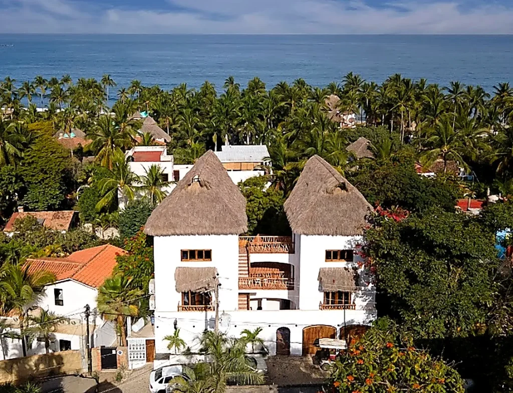 Aerial view of Amari Boutique Hotel's twin palapa towers above the Pacific coast in Sayulita, Nayarit