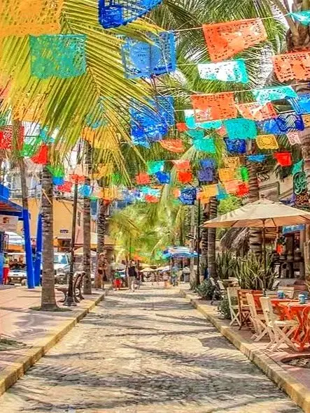 Colorful papel picado flags strung above a lively street in Sayulita, Nayarit, Mexico