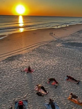 Group yoga class stretching on the sand at sunset on a Sayulita beach, Nayarit, Mexico